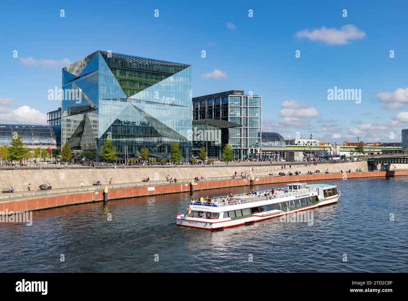 Ein Bild vom 3XN Cube Berlin Gebäude, dem Berliner Hauptbahnhof dahinter und einer Bootstour auf der Spree. Stockfoto