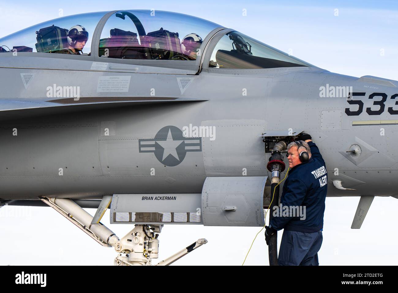 Jim Billingsley, T Square Logistics Services Aircraft Soldat, hilft beim Tanken eines EA-18G Growler der US Navy auf der Scott Air Force Base, Illinois, 13. Dezember 2023. Als Teil des Agile Combat Employment (ACE)-Konzepts der Luftwaffe ist das Betanken von Hot Pit entscheidend für den schnellen Einsatz von Truppen. (Foto der U.S. Air Force von Airman 1st Class Tyler A. P. Moody) Stockfoto