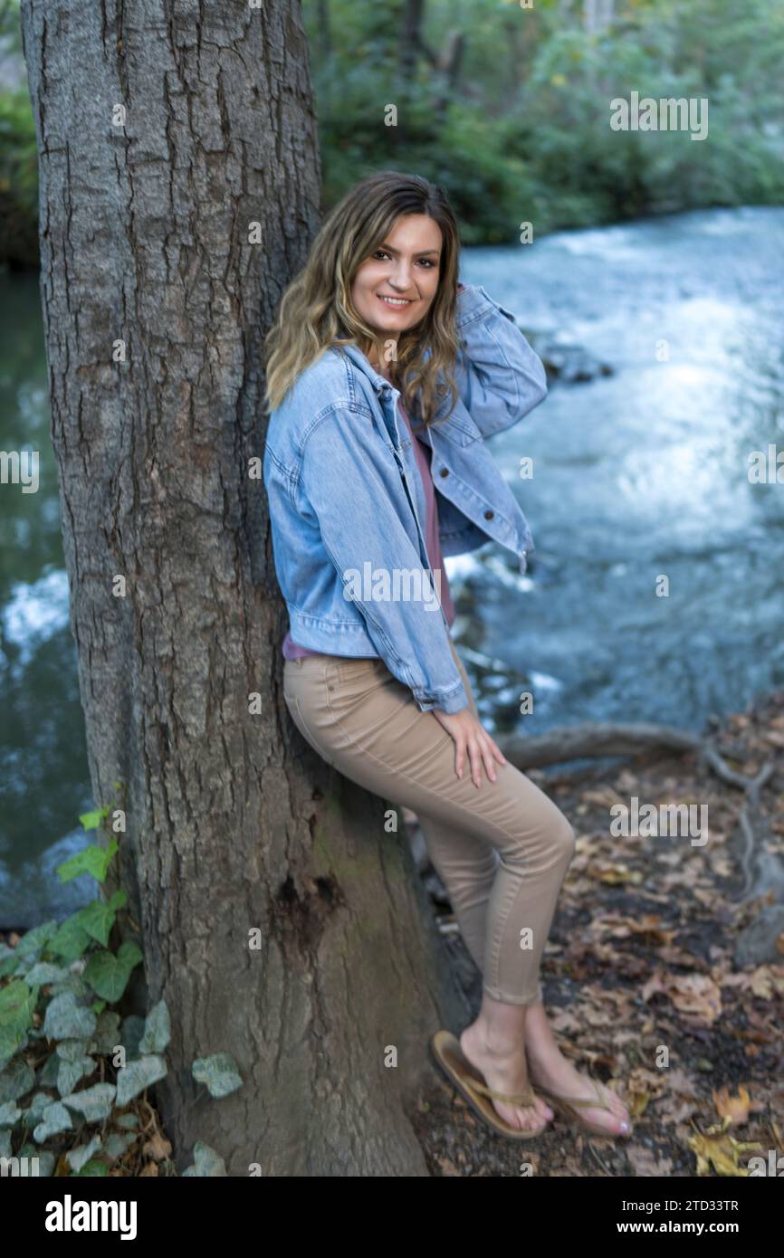 Attraktive junge Frau mit Denim-Jacke in Pastellfarben, die sich auf dem Tree Creek Wander Trail befindet Stockfoto