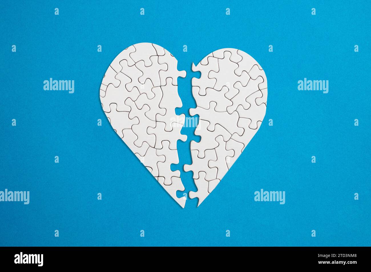 Gebrochene Herzform mit passenden Puzzleteilen auf blauem Hintergrund, abstrakte Nahaufnahme Stockfoto