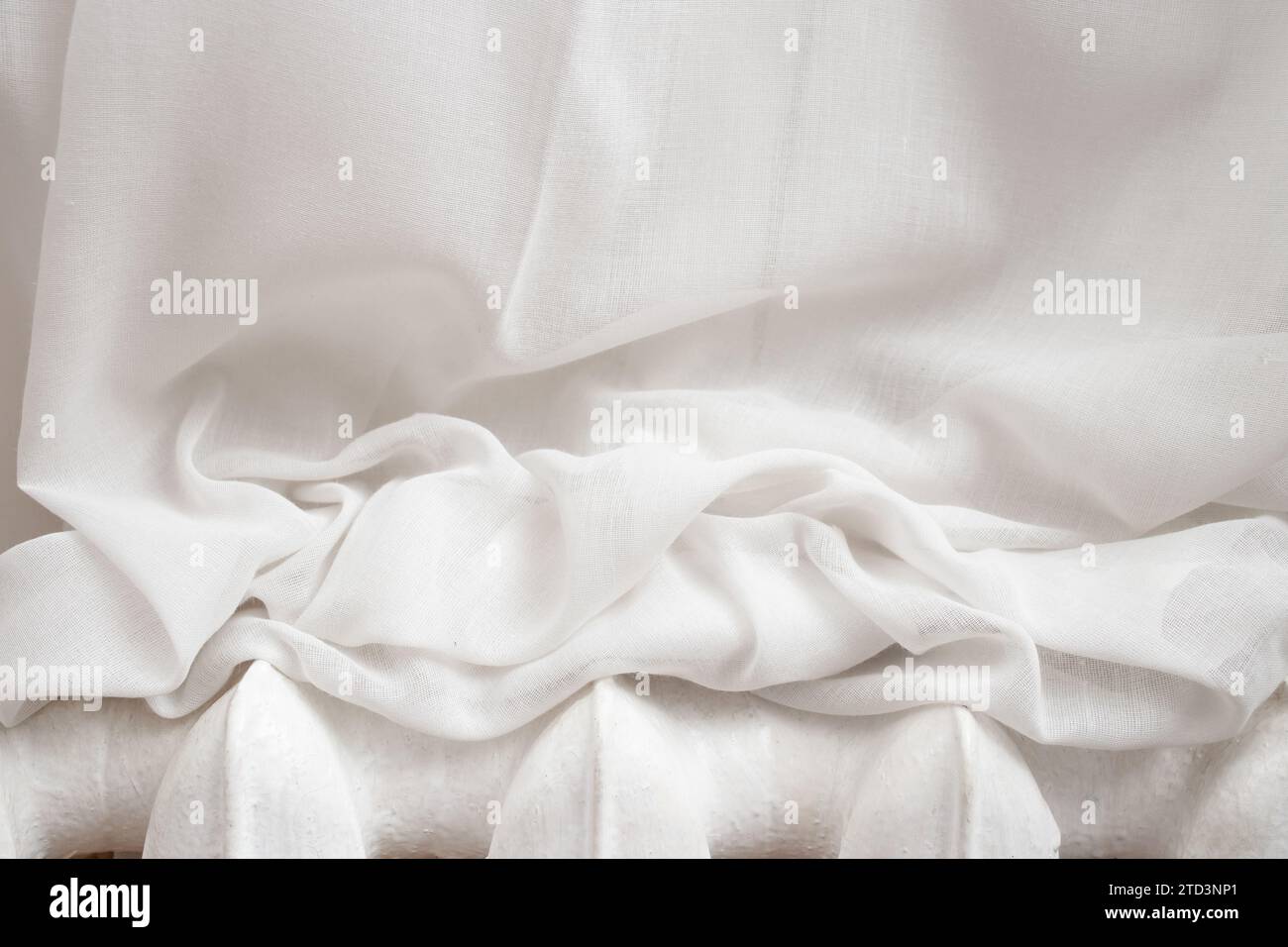 Weiße Vorhänge auf einer Metallheizung, abstrakte Textur Stockfoto