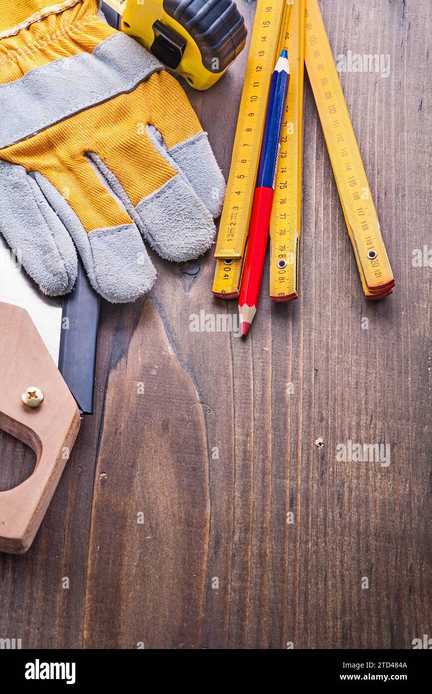 Komposition von Tischlerwerkzeugen Handschuhhandschuh Tapeline Holzmeterstift auf Vintage-Brettbaukonzept Stockfoto