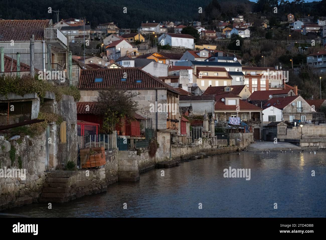 Malerische Stadt am Flussufer mit traditionellen Häusern in der Abenddämmerung, die eine ruhige europäische Dorfatmosphäre widerspiegeln. Stockfoto