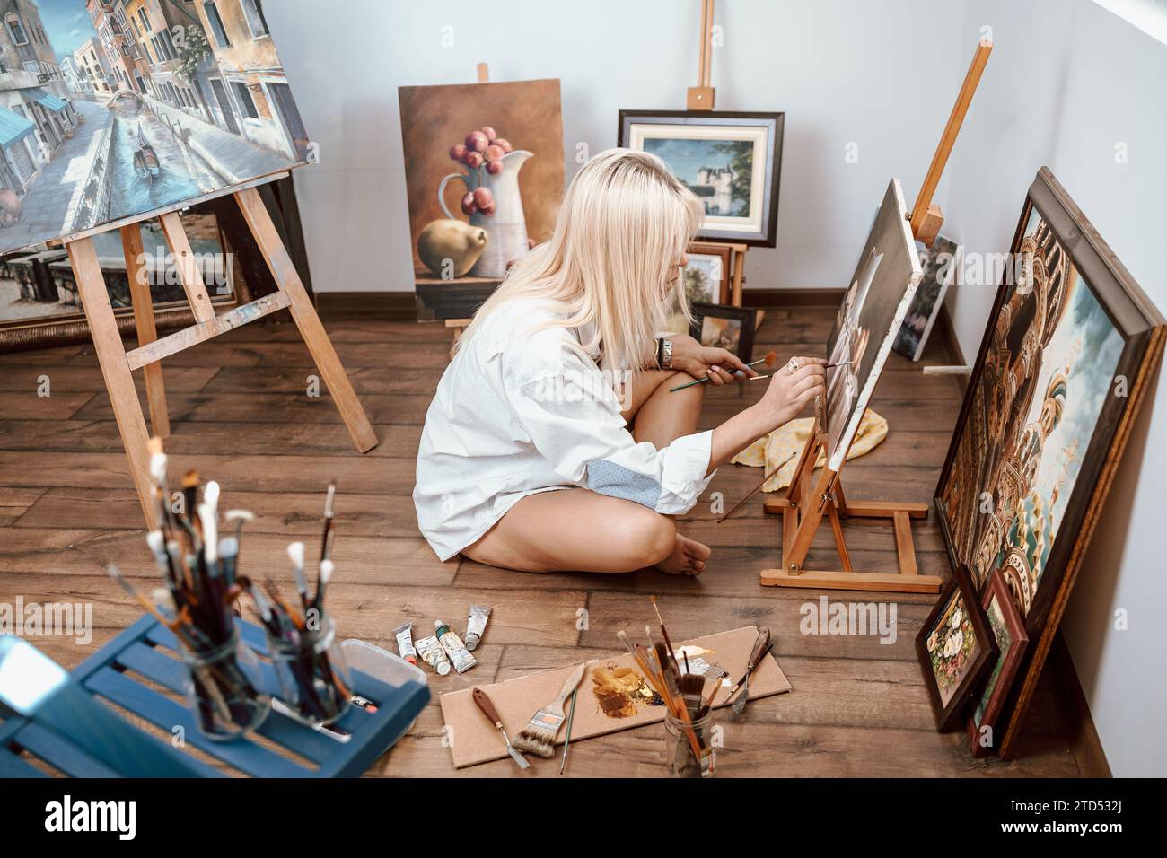 Eine junge, blonde Malerin, die ihr Kunstwerk zeigt Stockfoto