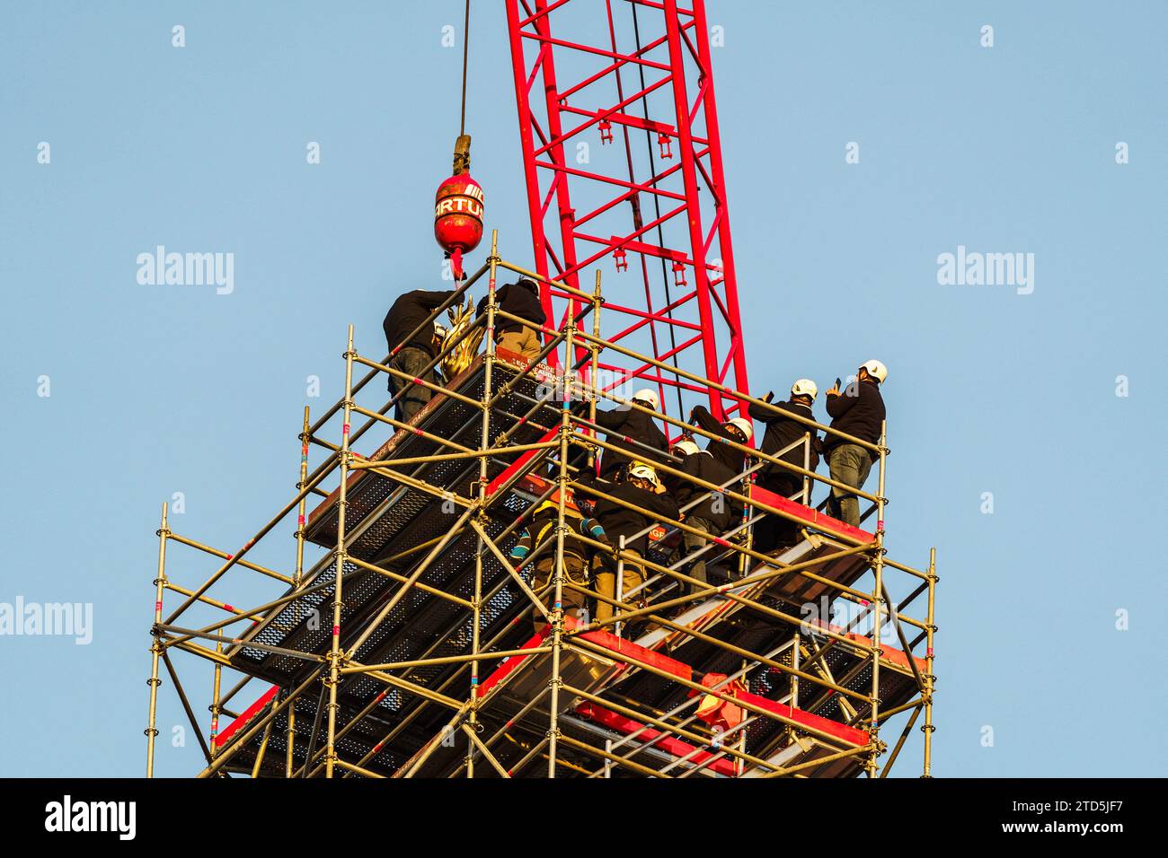 Der neue goldene Hahn mit Reliquien wird mit einem Kran angehoben und am 16. Dezember 2023 im Zentrum von Paris auf dem Turm der Kathedrale Notre Dame installiert. Der goldene Hahn, der vom Architekten Philippe Villeneuve entworfen wurde, enthält Reliquien, die von dem Brand gerettet wurden, der das Denkmal am 15. April 2019 traf, und ein Dokument mit den Namen der an seinem Wiederaufbau Beteiligten. Foto: Alexis Jumeau/ABACAPRESS.COM Stockfoto