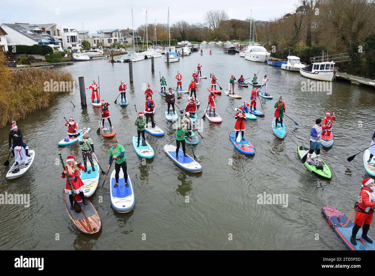 Gruppe von Paddelboardern, die als Santa und Elfen gekleidet sind. Weihnachtsveranstaltung organisiert von der BH Activity Junkieson the River Stour in Christchurch Dorset UK Stockfoto