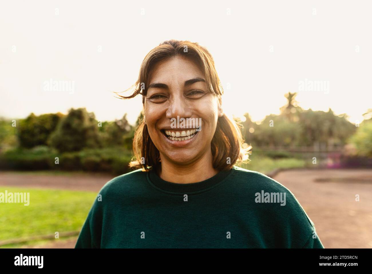 Glückliche Lateinfrau, die Spaß hat, in der Kamera in einem öffentlichen Park zu lächeln Stockfoto
