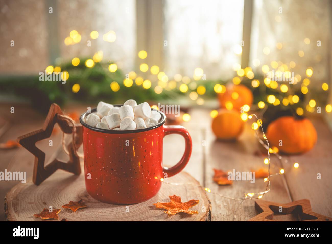 Niedliche, gemütliche Winterkomposition. Rote Tasse, Marshmallows, Orangen und Weihnachtslichter. Silvester und weihnachten, Wärme, Komfort Stockfoto