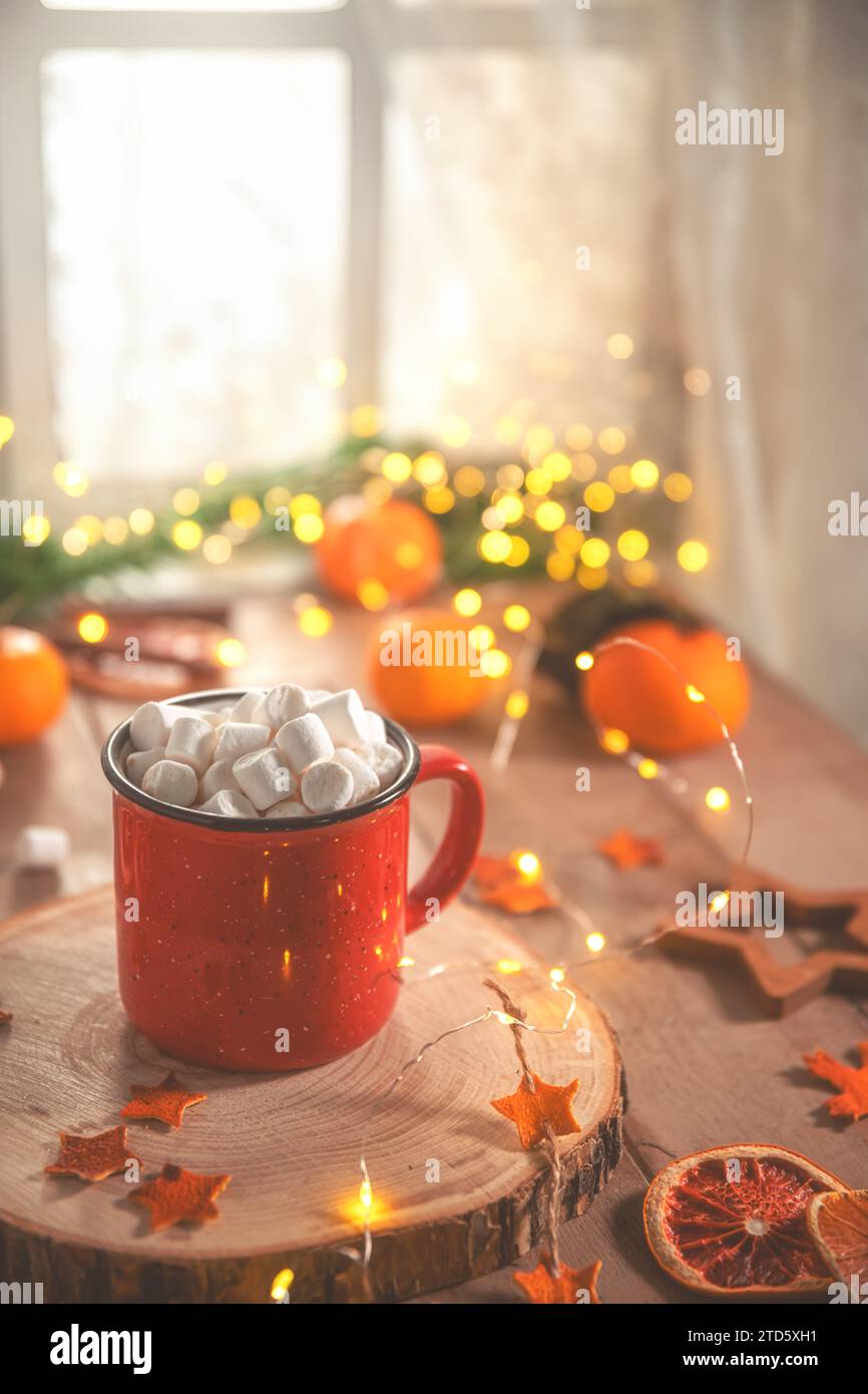 Niedliche, gemütliche Winterkomposition. Rote Tasse, Marshmallows, Orangen und Weihnachtslichter. Silvester und weihnachten, Wärme, Komfort Stockfoto