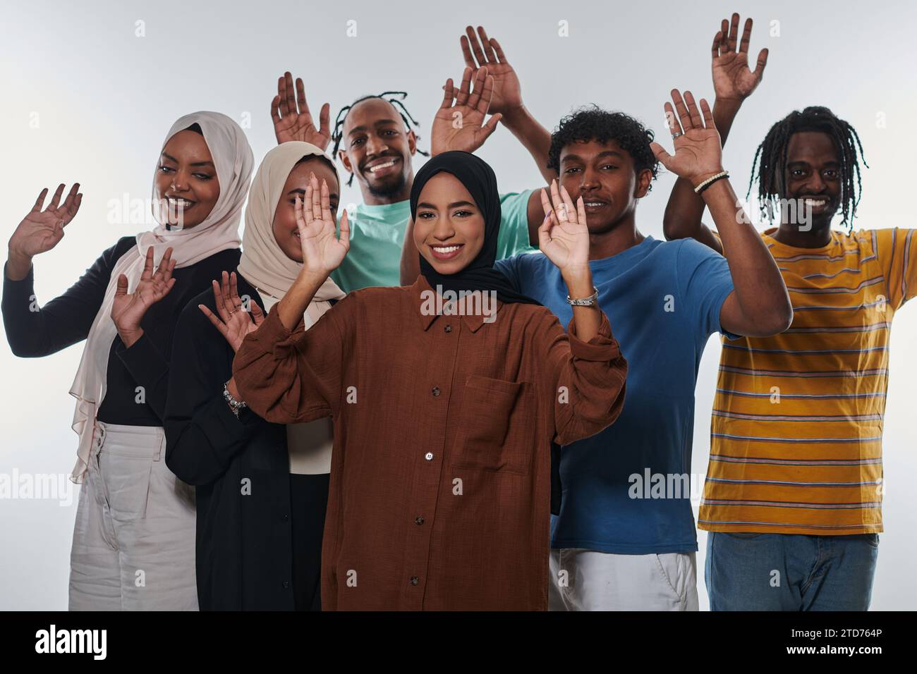 Eine jubelnde und vielfältige Gruppe, darunter ein Afroamerikaner und Hijab tragende Mädchen, winken und feiern überschwänglich und verkörpern die Lebendigkeit von Stockfoto