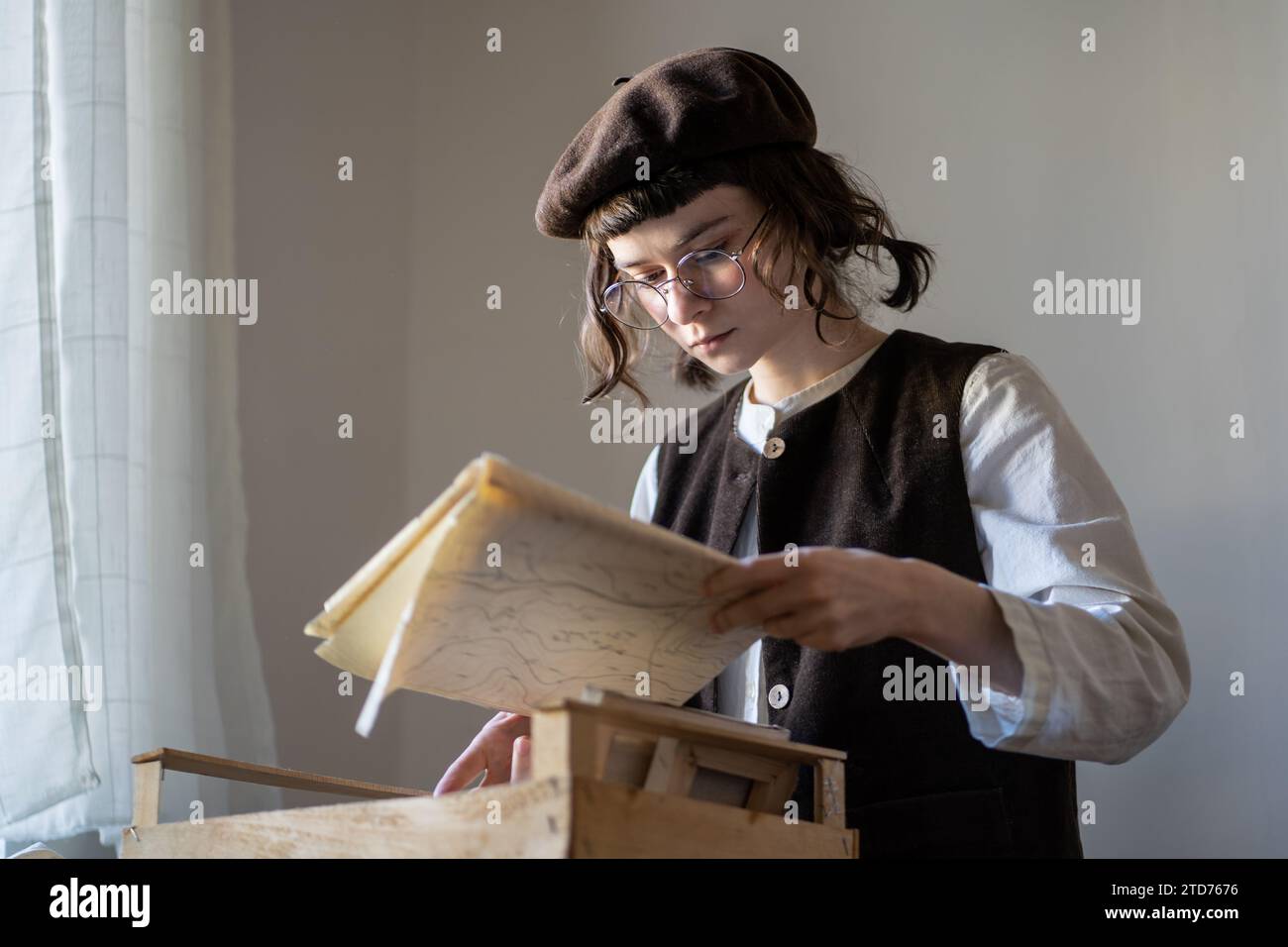 Interessierte Kunststudentin Malerin studiert aufmerksam Papierprojekt Skizzen im Unterricht. Stockfoto