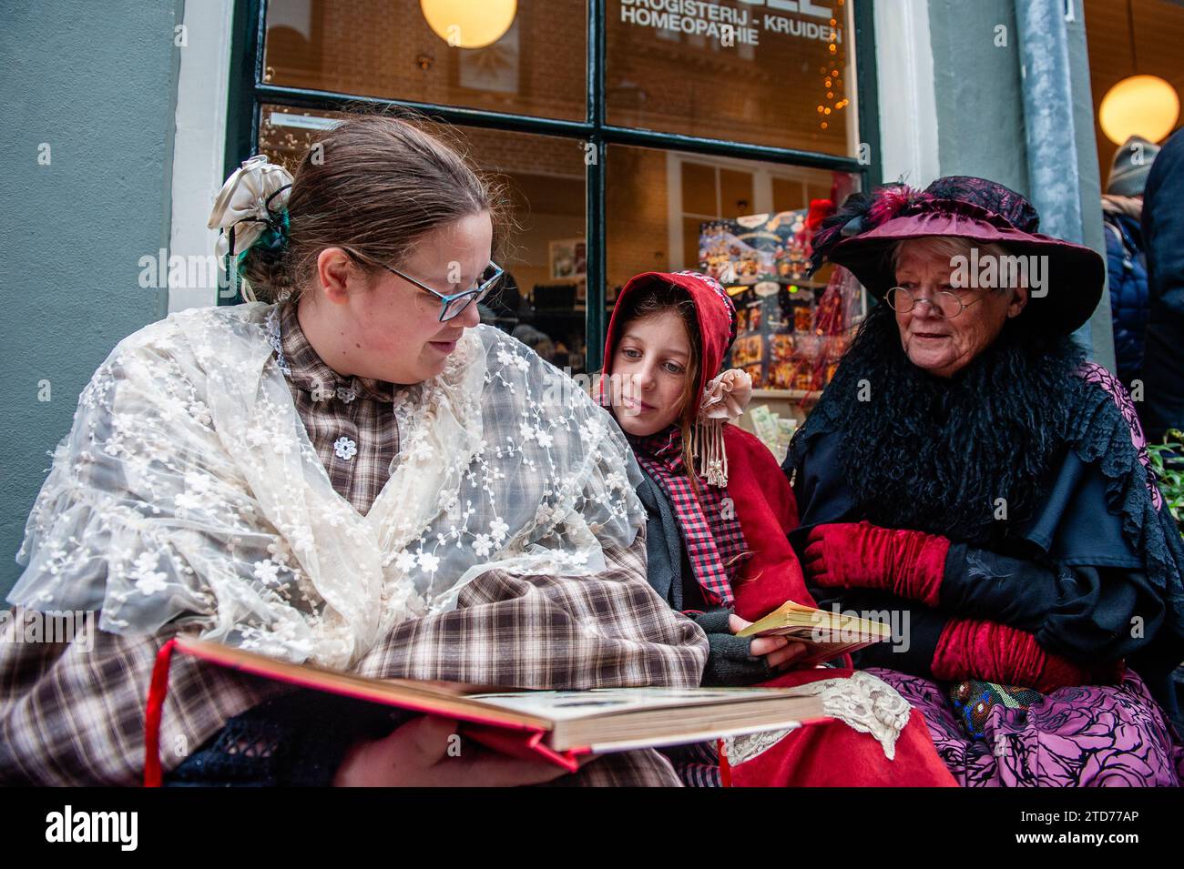 Deventer, Niederlande . Dezember 2023. Drei Frauen werden gesehen, wie sie ein Buch über viktorianische Kostüme lesen. Jedes Jahr, um dieses Datum, lebt die Welt des englischen Schriftstellers Charles Dickens aus dem 19. Jahrhundert in der schönen niederländischen Stadt Deventer wieder. Mehr als 950 Charaktere aus den berühmten Büchern von Dickens zurück ins Leben. Wohlhabende Damen und Herren mit Spitzhüten ziehen durch die Straßen. Die Landschaft des Festivals besteht aus historischen Gebäuden, Weihnachtsbäumen und Tausenden von kleinen Lichtern. Quelle: SOPA Images Limited/Alamy Live News Stockfoto