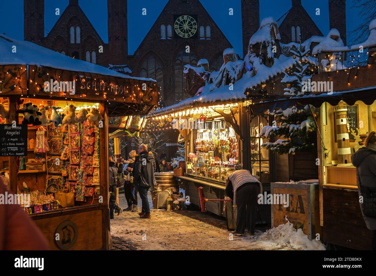 Lübeck, 6. Dezember 2023: Beleuchtete Verkaufsstände mit Schnee auf den Dächern auf dem Weihnachtsmarkt in der historischen Altstadt von Lübeck, Kopie Stockfoto