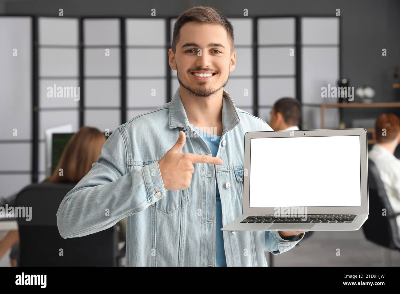 Männlicher Programmierer, der auf leeren Laptop im Büro zeigt Stockfoto