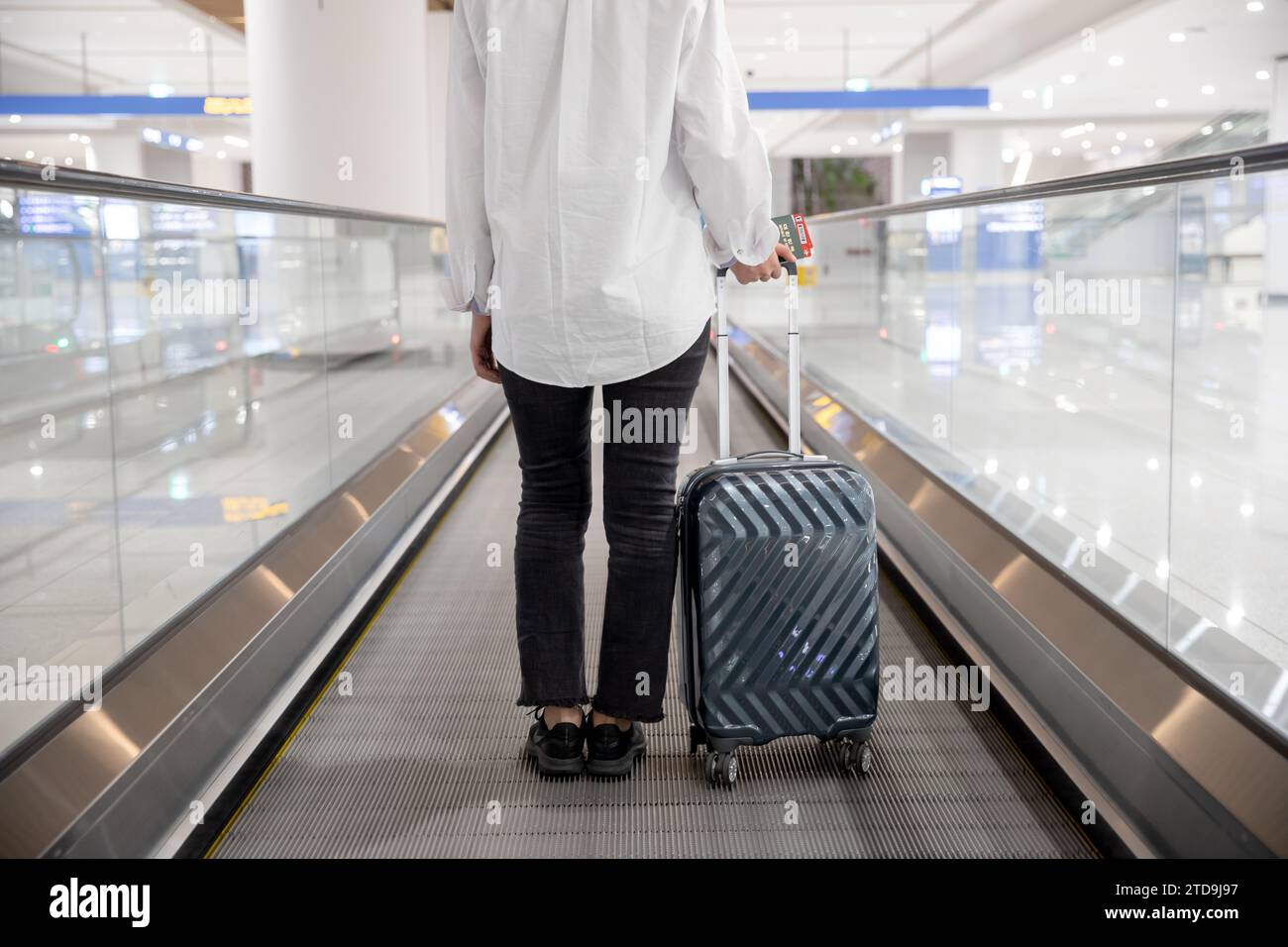 Rückansicht einer Frau, die sich mit einer Rolltreppe am Flughafen bewegt Stockfoto