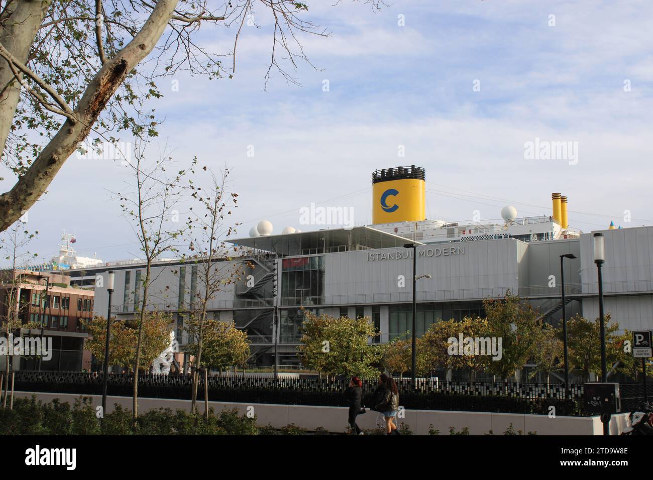 Fassade der Istanbul Modern Art Gallery mit dem großen gelben Trichter eines Kreuzfahrtschiffes dahinter Stockfoto