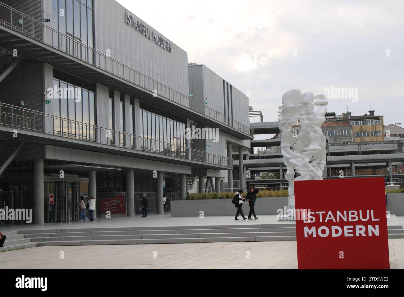 Vorderseite der Istanbul Modern Art Gallery, entworfen von Renzo Piano, mit rotem Schild und Tony Craggs weißer Skulptur „Runner“ Stockfoto