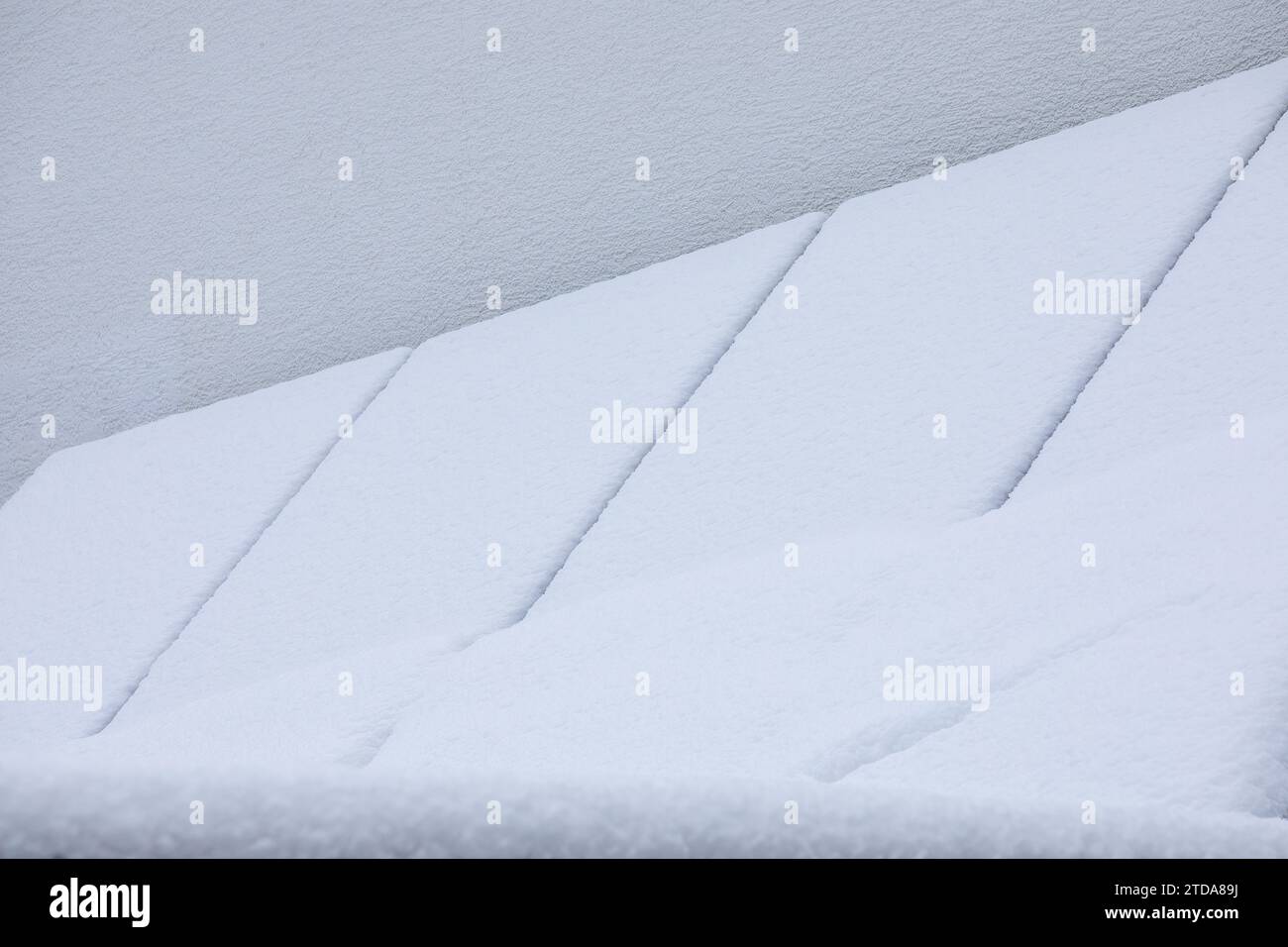 Schneebedeckte Sonnenkollektoren auf einer Garage: Winterfeste erneuerbare Energien Stockfoto