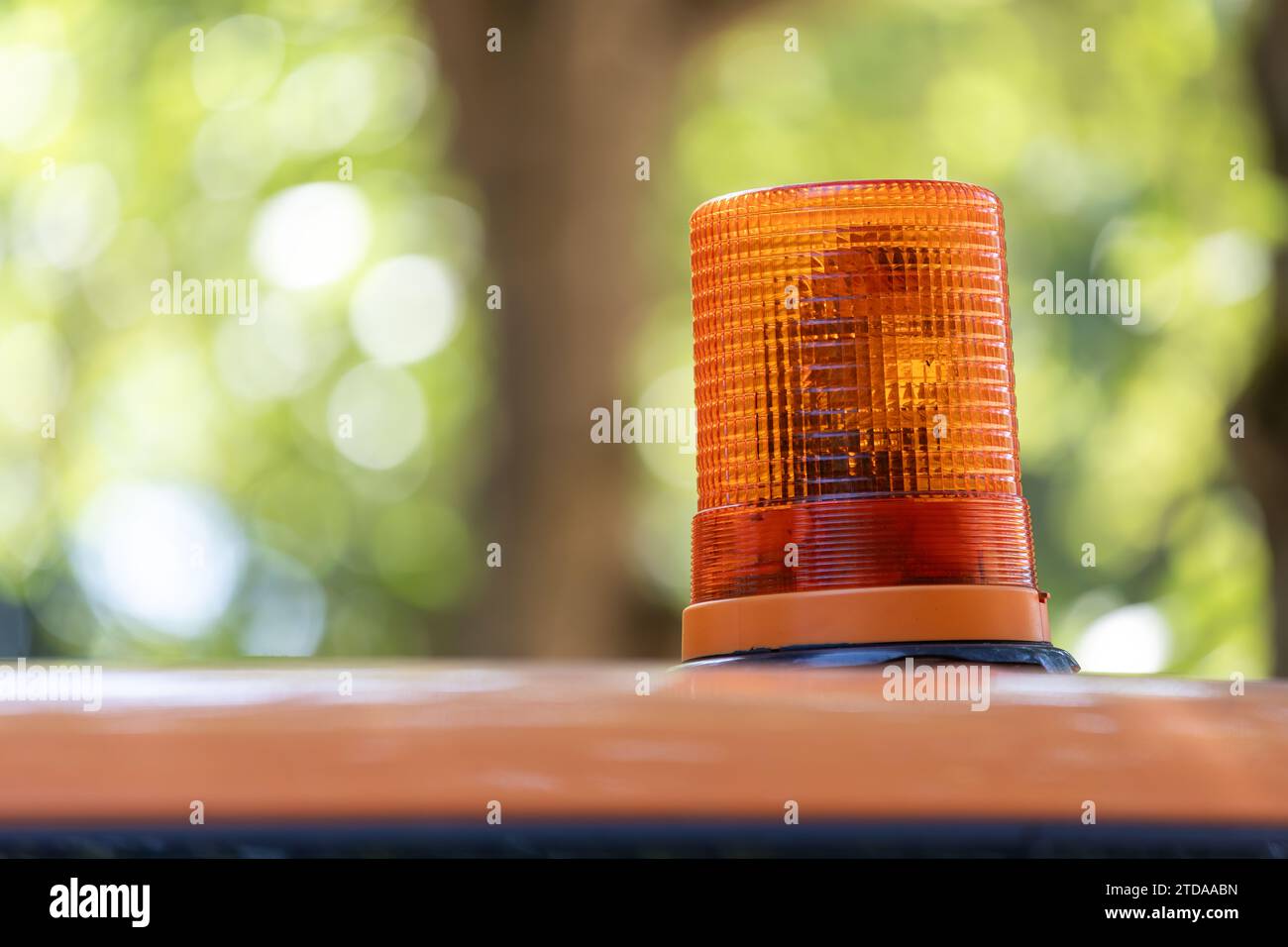 Erhöhte Sicherheit: Leuchtendes orangefarbenes Warnlicht auf dem Landschaftsgestaltungsfahrzeug inmitten eines unscharfen Hintergrunds Stockfoto