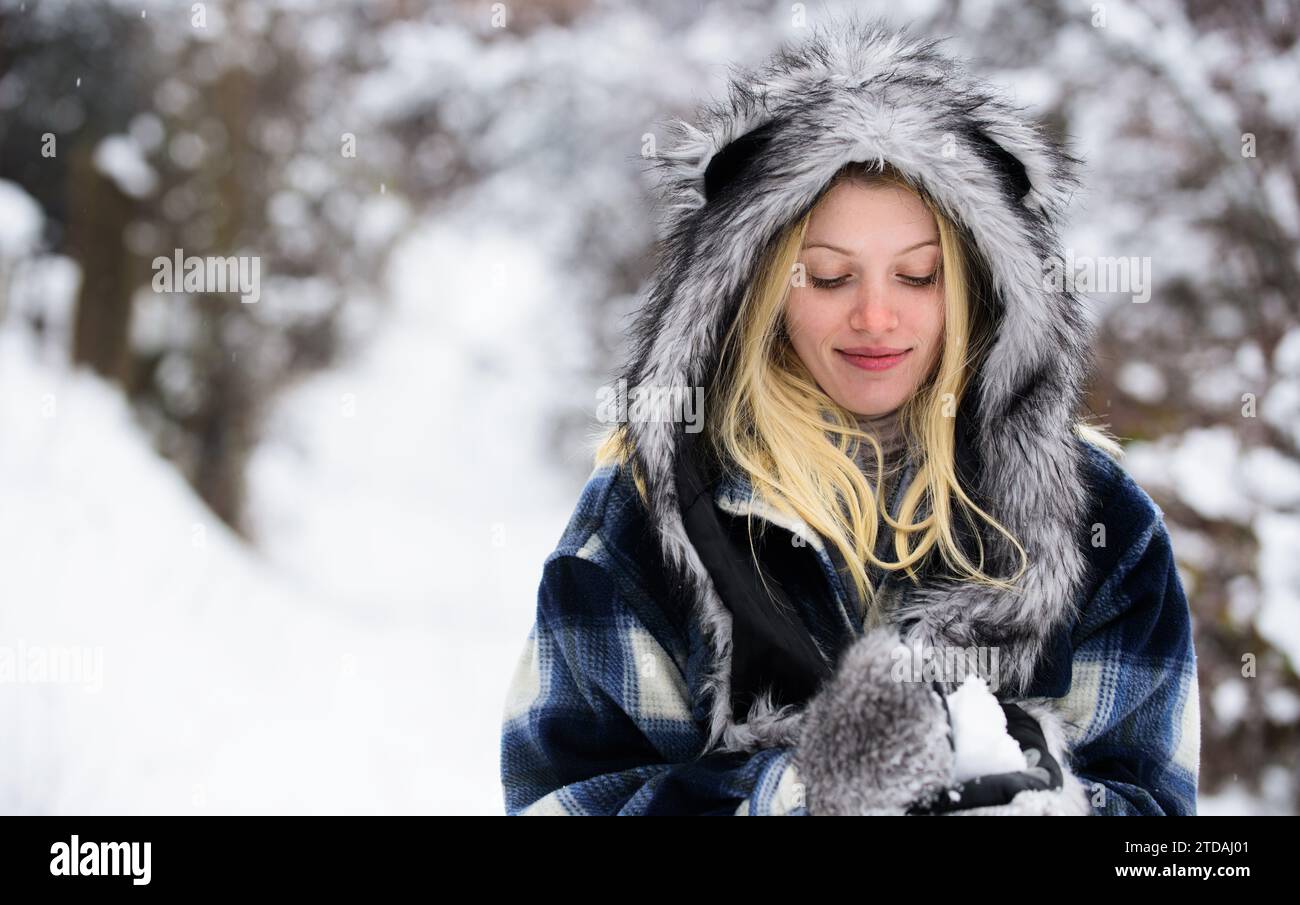Hübsche Frau in stilvoller Kleidung mit Schneebälle in den Händen. Lächelndes Mädchen in warmer Kleidung, das mit Schnee im Winterpark spielt. Schöne Frau im karierten Mantel Stockfoto
