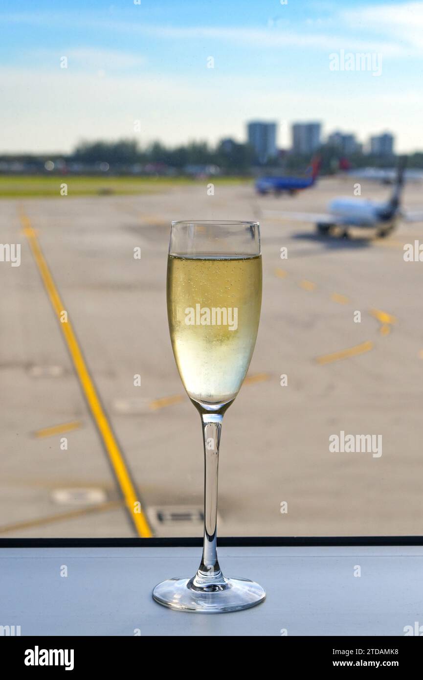 Flöte Glas gekühlten Champagner auf der Fensterbank einer Flughafenlounge mit Flugzeugen im Hintergrund Stockfoto