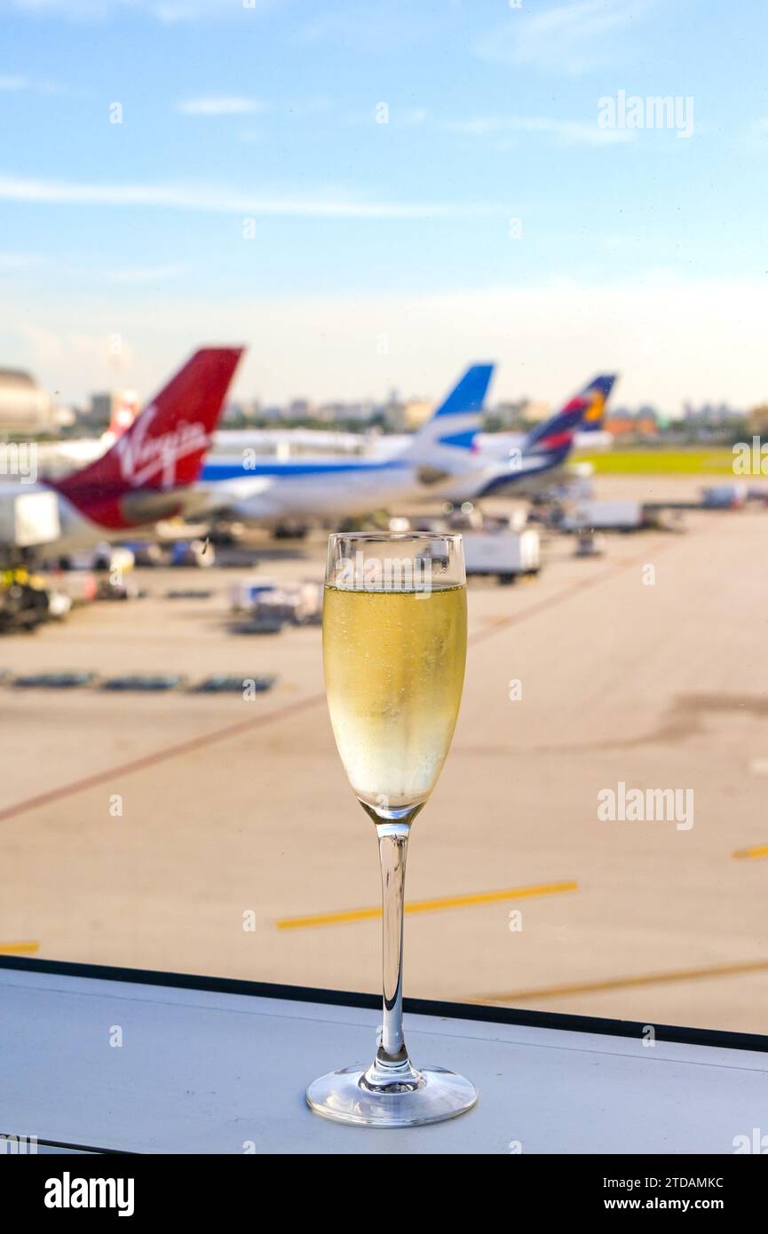 Miami, Florida, USA - 5. Dezember 2023: Flötenglas mit gekühltem Champagner auf dem Fenstervorsprung einer Flughafenlounge. Stockfoto