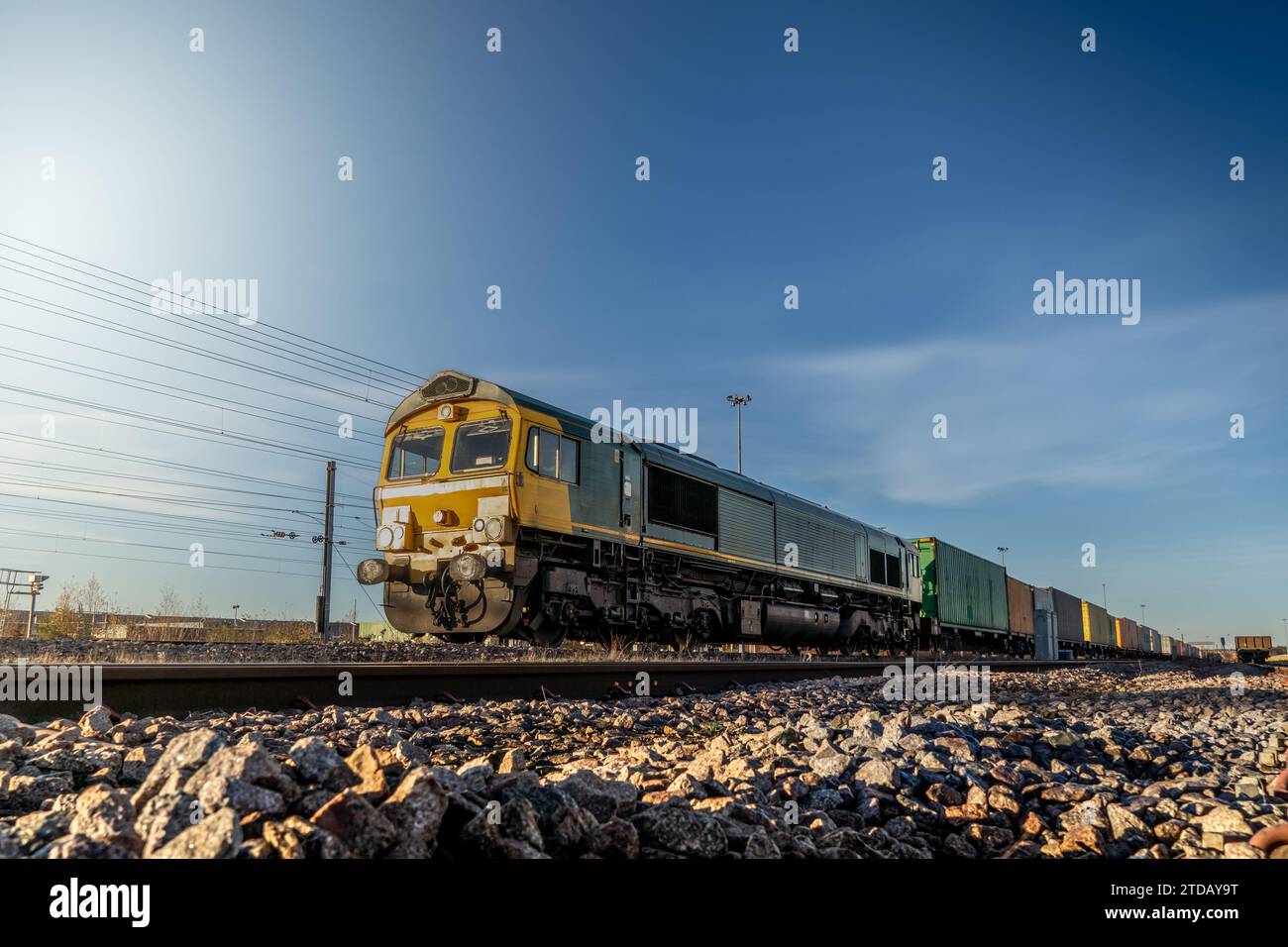 Profilansicht eines Güterzugs mit Intermodalwagen voller Container für den Import und Export auf einem Hof oder Anschlussgleisen Stockfoto