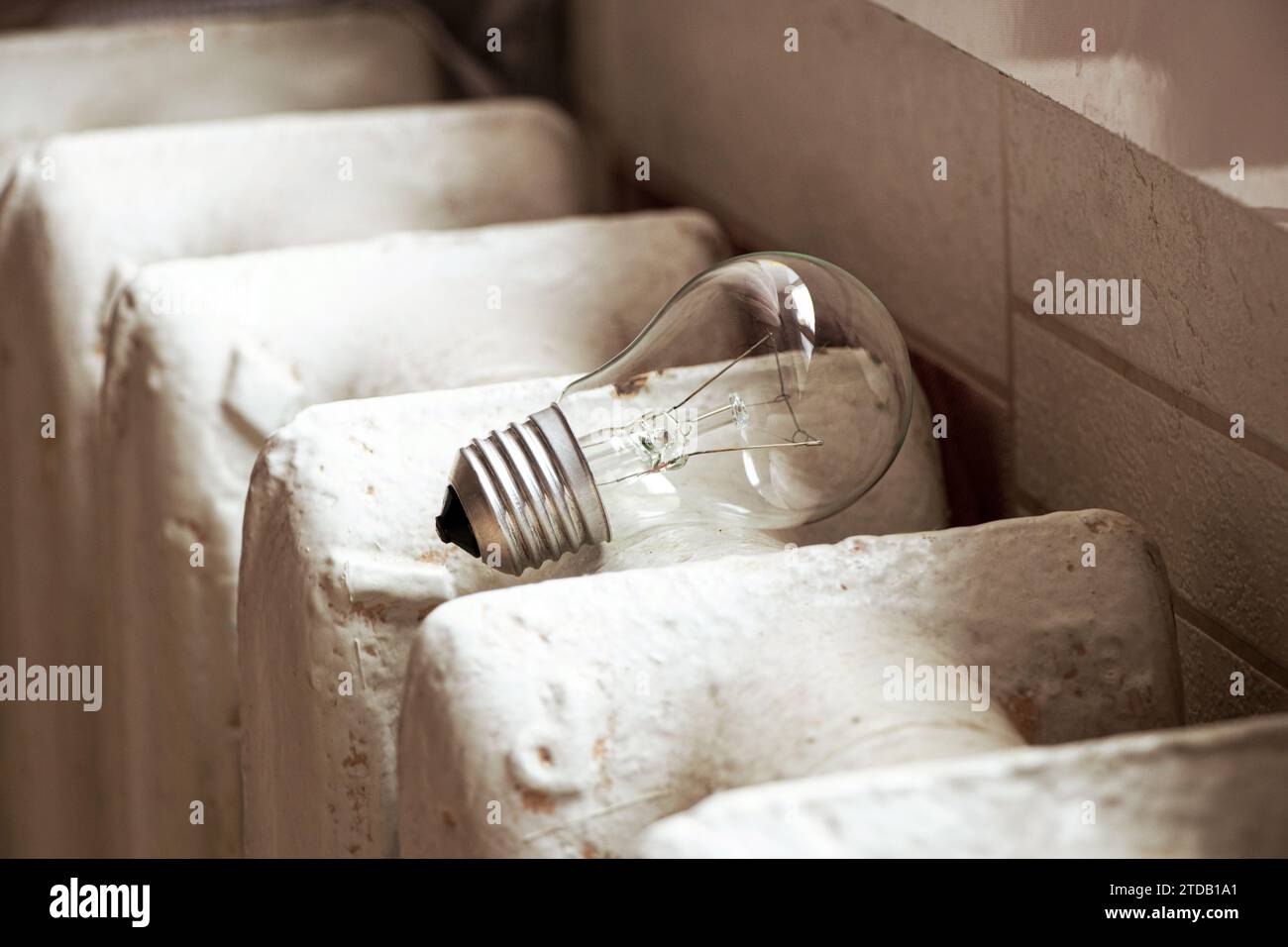 Glühlampe und Gusseisenbatterie in einer Wohnung in der Ukraine für die Küche, Licht und Wärme im Haus, Versorgungseinrichtungen Stockfoto