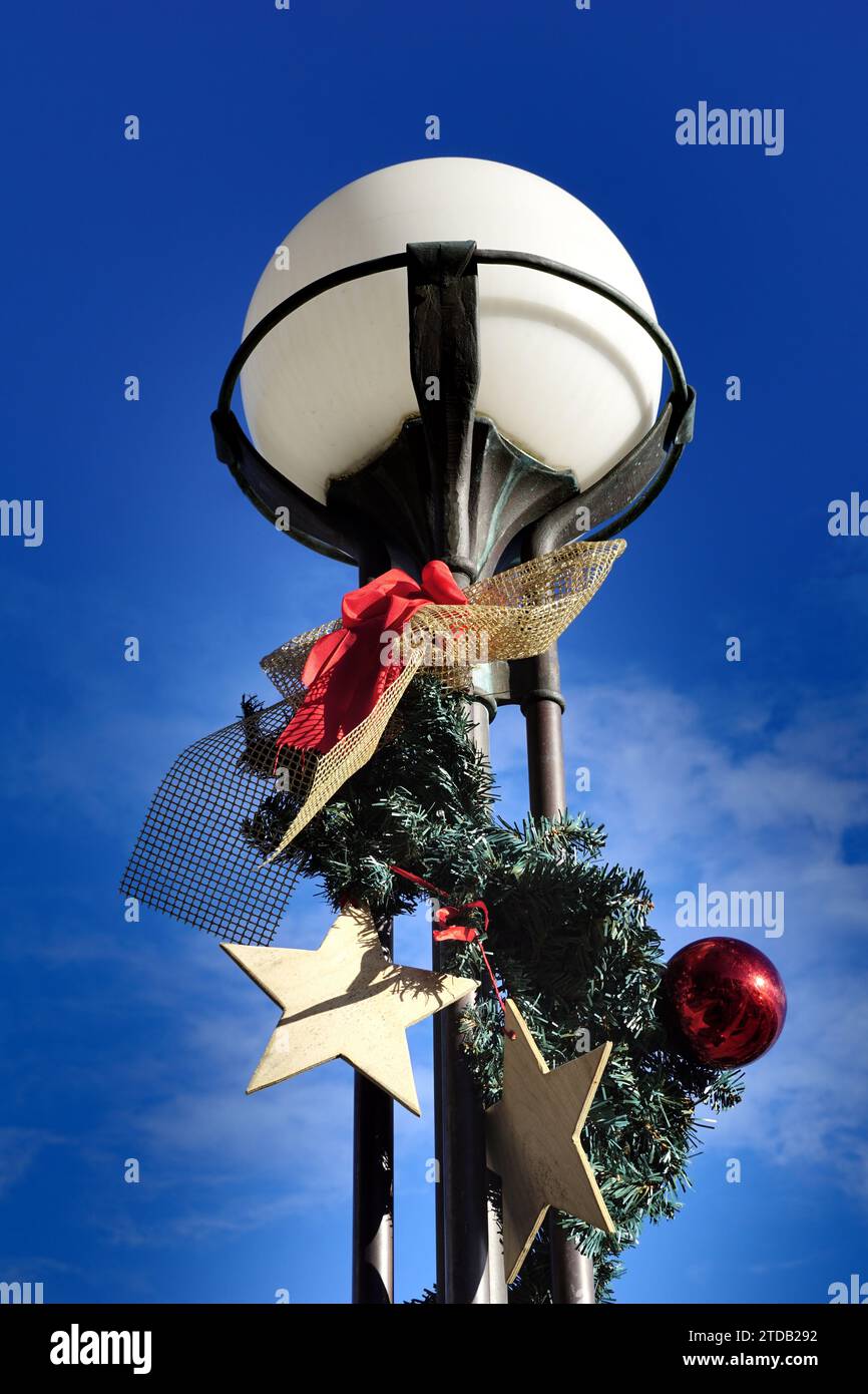 Straßenlaterne mit Weihnachts- und Feiertagsdekorationen vor blauem Himmel an sonnigen Tagen Stockfoto