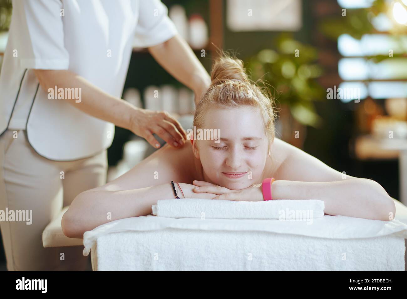 Gesundheitszeit. Weibliche medizinische Massage-Therapeutin im Massageschrank mit Teenager-Klientin, die Massage auf Massagetisch macht. Stockfoto