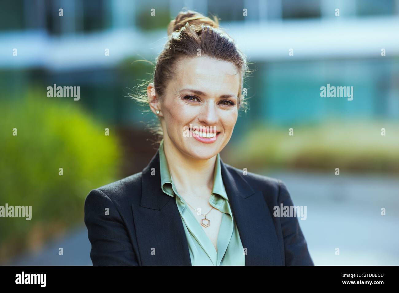 Porträt einer glücklichen modernen Arbeiterin der Nähe des Bürogebäudes in schwarzer Jacke. Stockfoto