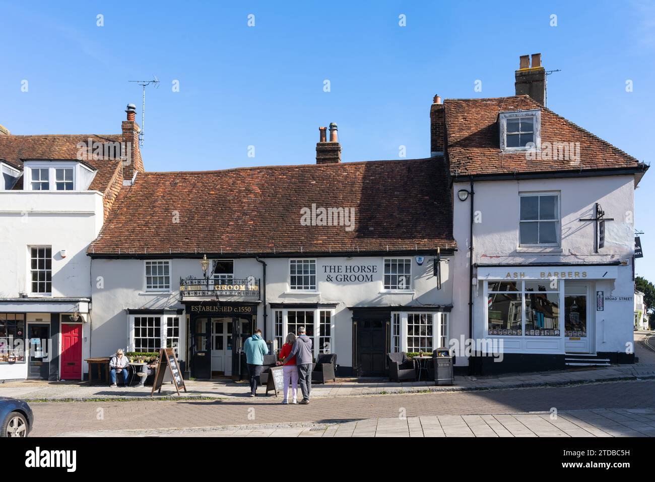 Im The Horse and Bräutigam, einem rustikalen Pub und Restaurant mit echten Bieren auf der Broad Street in New Alresford, Großbritannien, sitzen Leute draußen in der Sonne Stockfoto