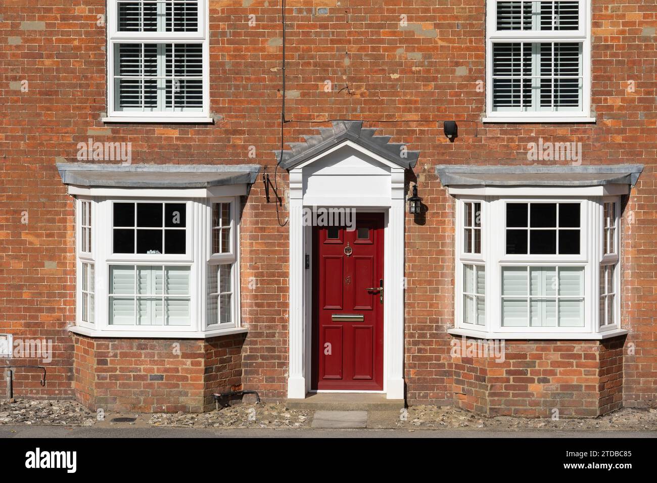 Traditionelles typisches englisches georgianisches Stadthaus mit einer offenen weißen georgianischen Veranda und einer roten Eingangstür. New Alresford, England Stockfoto