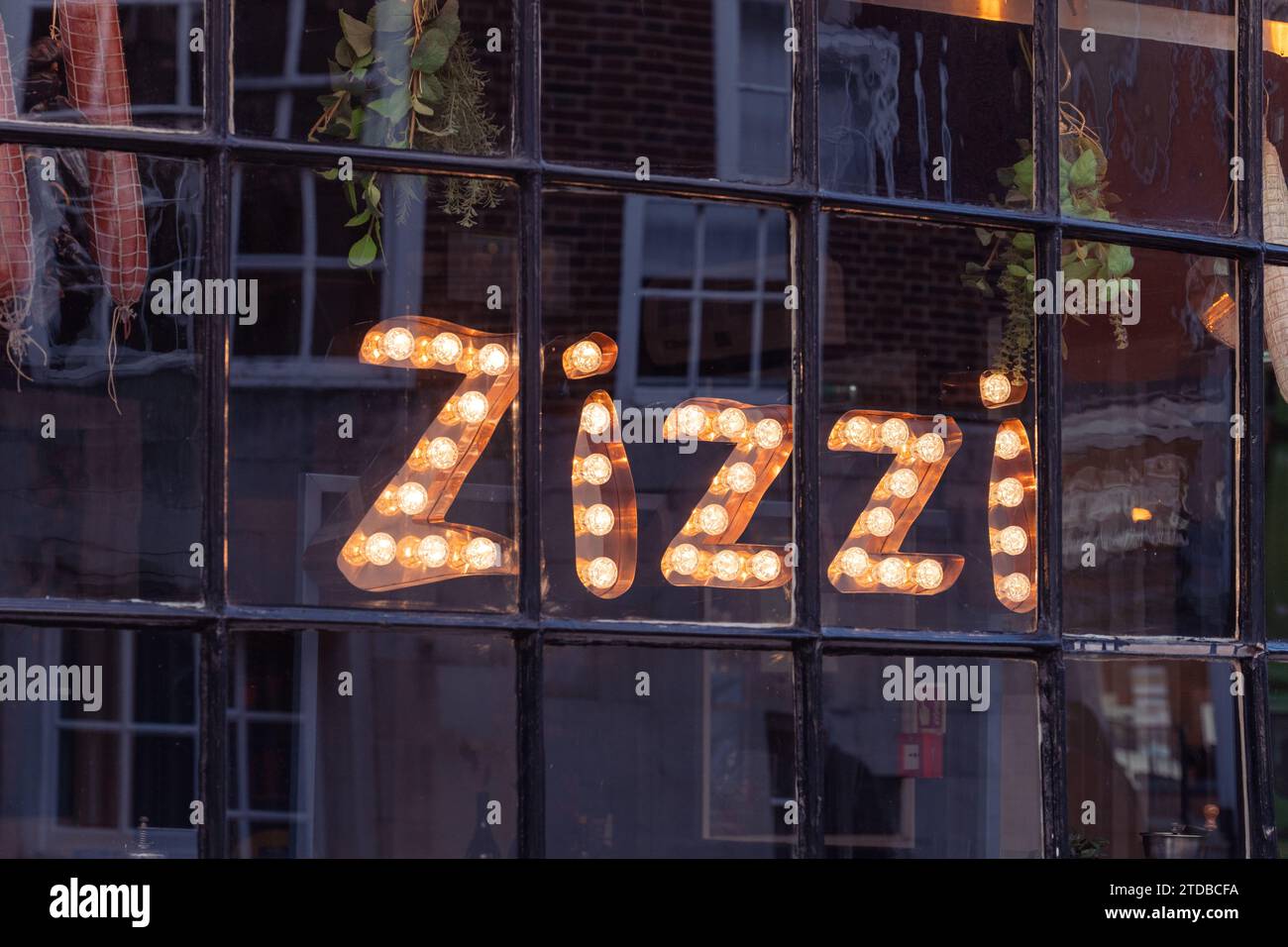 Beleuchtetes Schild aus Glühbirnen im vorderen Fenster eines Zizzi Restaurants an der Winchester High Street, Großbritannien. Die Azzurri-Gruppe betreibt Zizzi Stockfoto