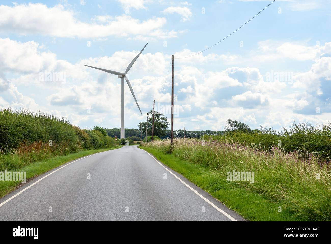 Windkraftanlage entlang einer kurvenreichen Straße in England an einem teilweise bewölkten Sommertag Stockfoto