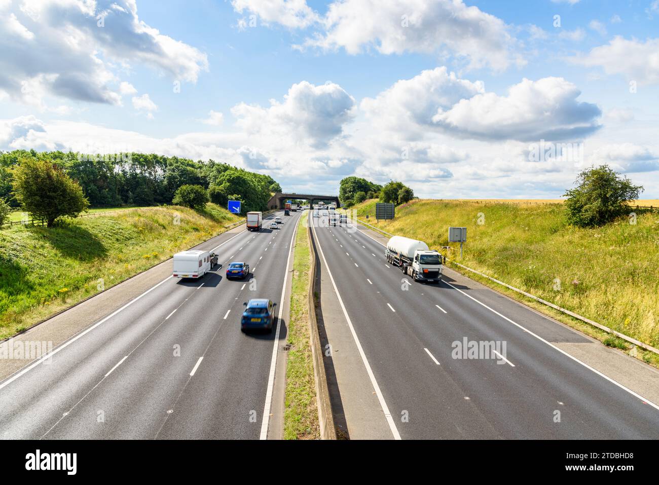 Verkehr auf einer dreispurigen Autobahn, die an einem sonnigen Sommertag durch die englische Landschaft führt Stockfoto