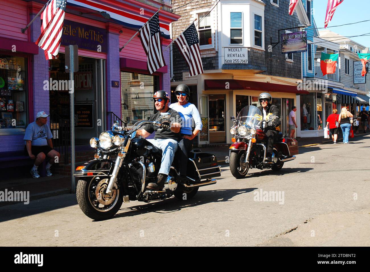 An einem sonnigen Sommerferientag tummeln sich zwei Motorräder durch die historische Innenstadt von Provincetown, Cape Cod, Massachusetts Stockfoto