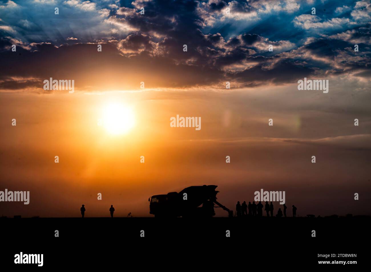 Bauland am Hafen, Sandwagen und Arbeiter können bei Sonnenuntergang und sichtbaren Silhouetten gesehen werden Stockfoto