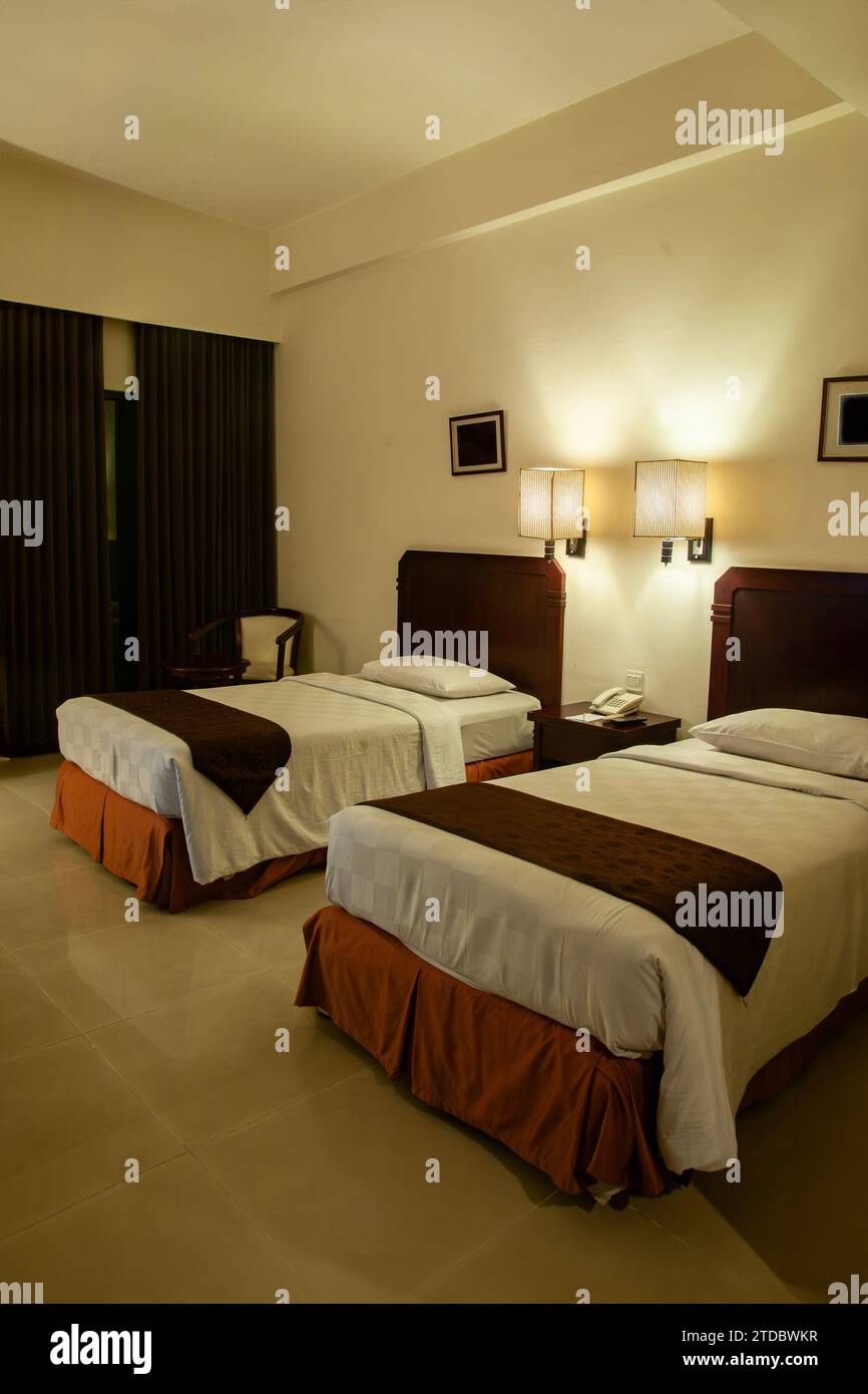 Hotelzimmer mit zwei Einzelbetten, gedämpfter Innenbeleuchtung Stockfoto