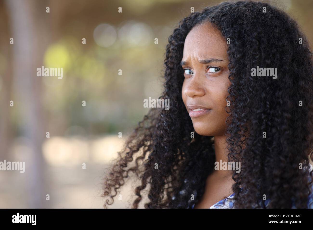 Eine verärgerte schwarze Frau, die in einem Park in die Kamera schaut Stockfoto