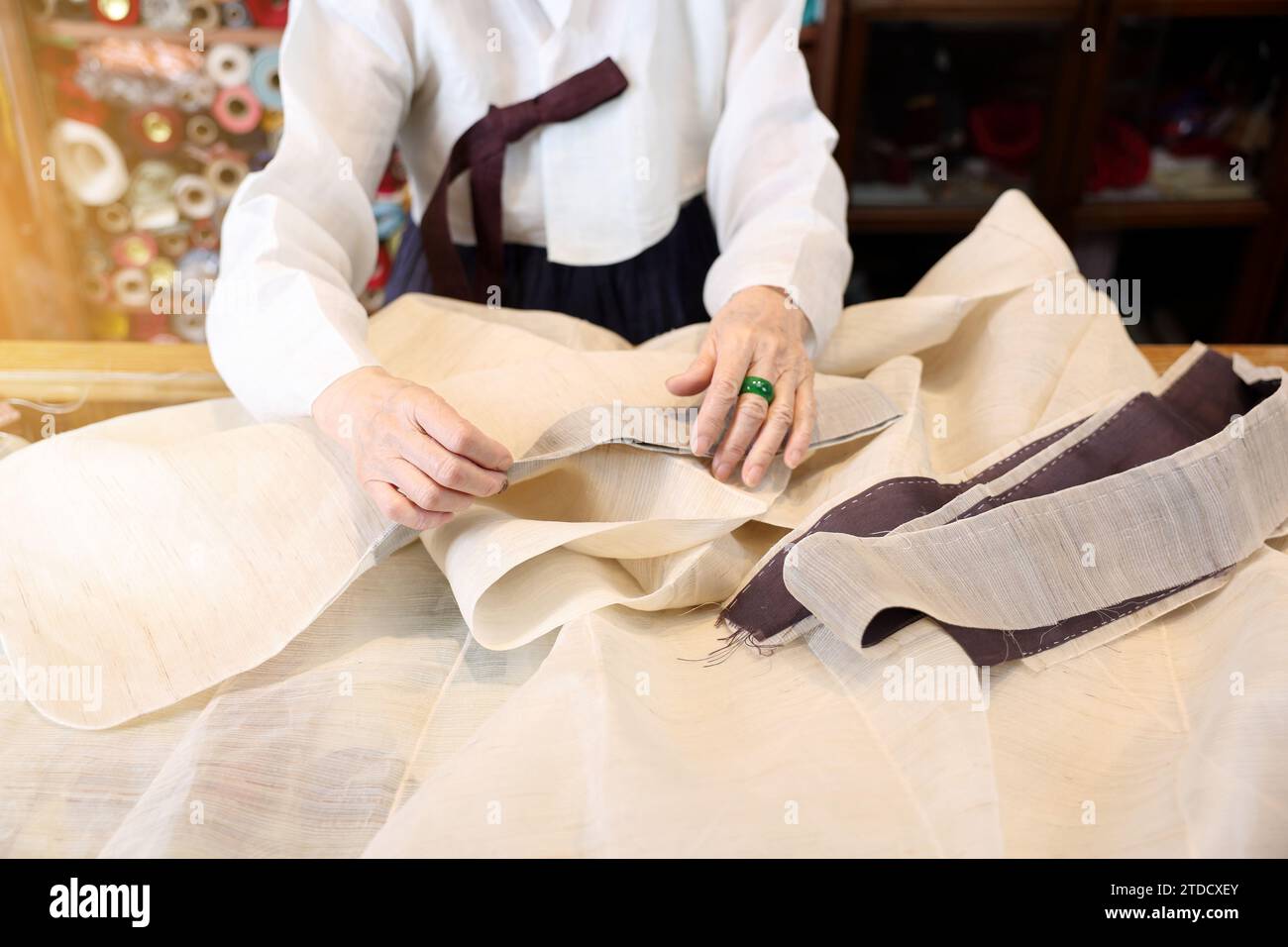 Ein Meister traditioneller koreanischer Kleidung, ein Hanbok-Experte, näht für die Hanbok-Produktion. Stockfoto