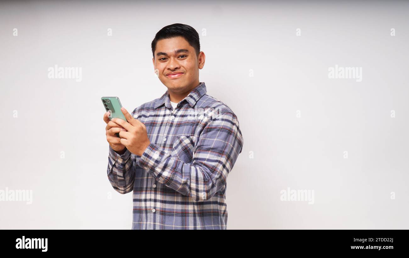 Junger asiatischer Mann, der ein Handy hält und enthusiastischen Ausdruck zeigt Stockfoto