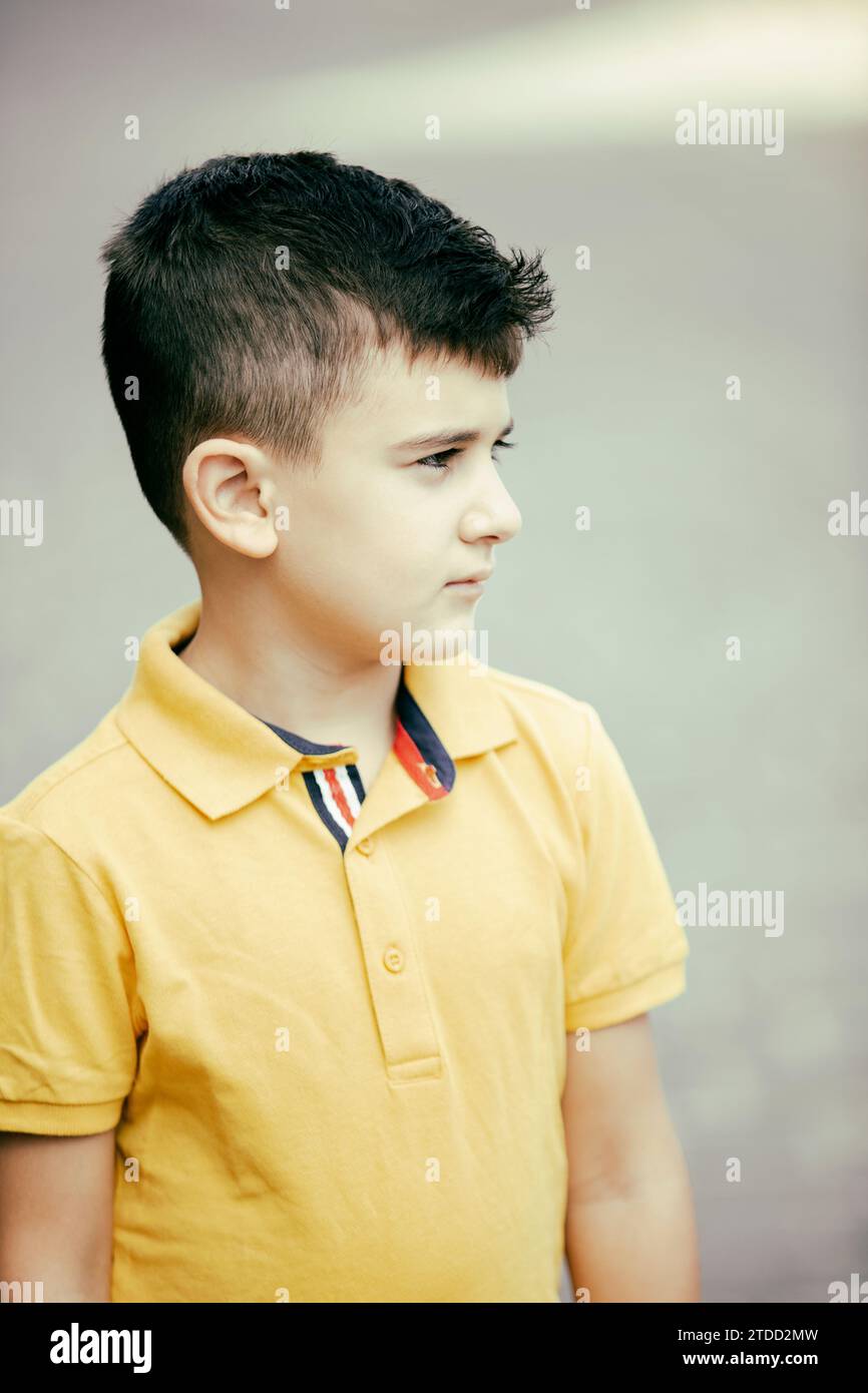 8 Jahre alter Junge, der draußen steht und wegschaut Stockfoto