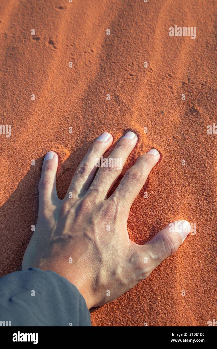 Die linke Hand liegt auf rotem Wüstensand von Wadi Rum, Jordanien Stockfoto