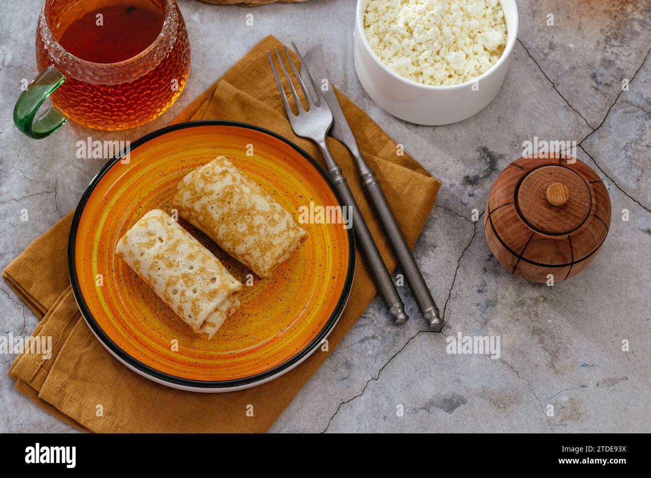 Pfannkuchen mit Hüttenkäse auf einem Teller. Tee in einer Tasse. Stockfoto