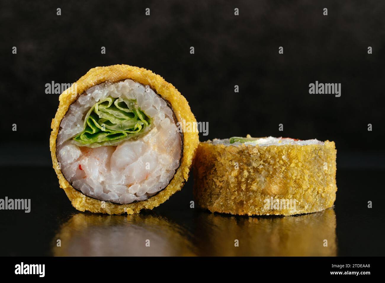 Frittierte japanische Sushi-Rollen auf dunklem Hintergrund mit Reflektor Stockfoto