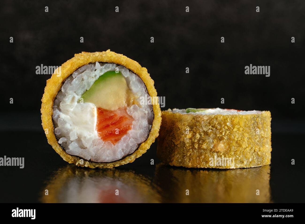 Frittierte japanische Sushi-Rollen auf dunklem Hintergrund mit Reflektor Stockfoto