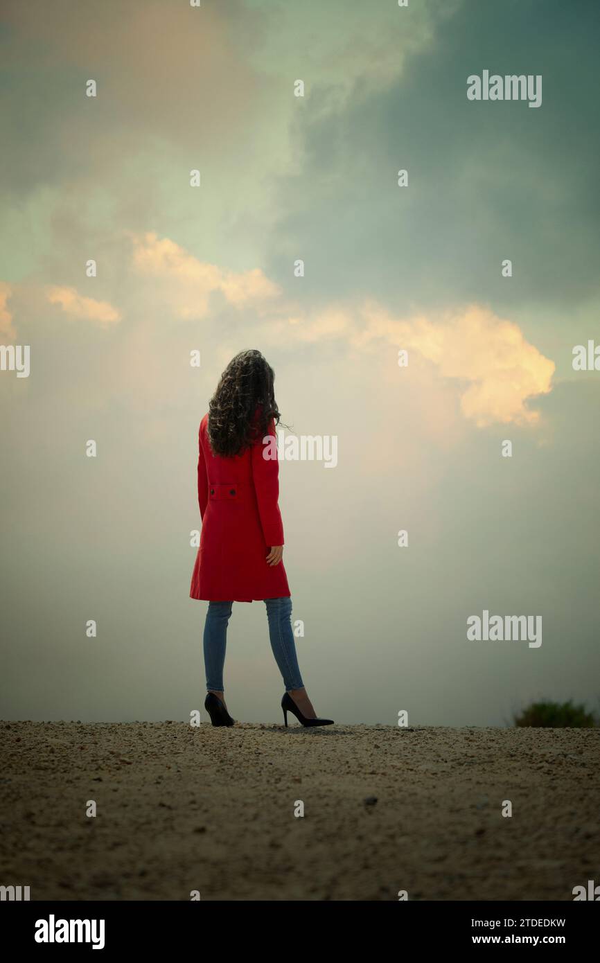 Rückansicht einer Frau im roten Mantel, die draußen steht Stockfoto