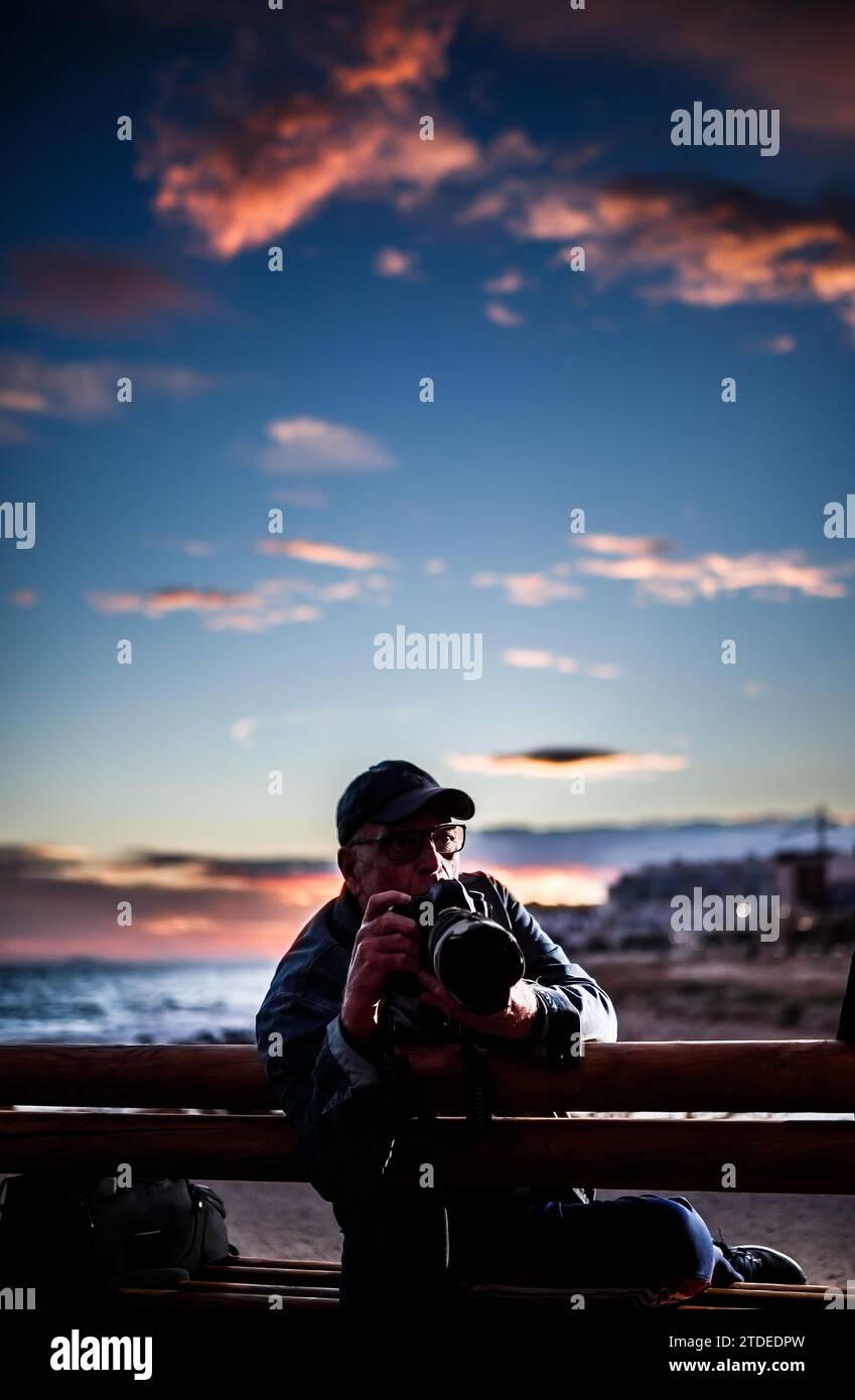 Ruhiger Mann, der auf der Bank sitzt und Fotos macht Stockfoto