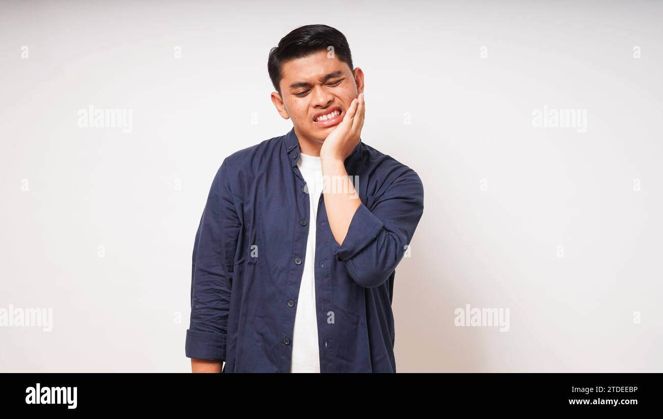 Zahnschmerzkonzept. Asiatischer Mann, der seinen Kiefer mit Schmerzausdruck auf weißem Hintergrund berührt. studio-Aufnahme Stockfoto